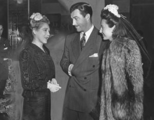 Photograph caption dated April 2, 1943 reads, "Hollywood was charmed by China's First Lady. Among those caught by her beauty and magnetism were, left to right, Mary Pickford, Robert Taylor and Barbara Stanwyck. The Missimo walked casually about the Gold Room as she visited with the stars." 
